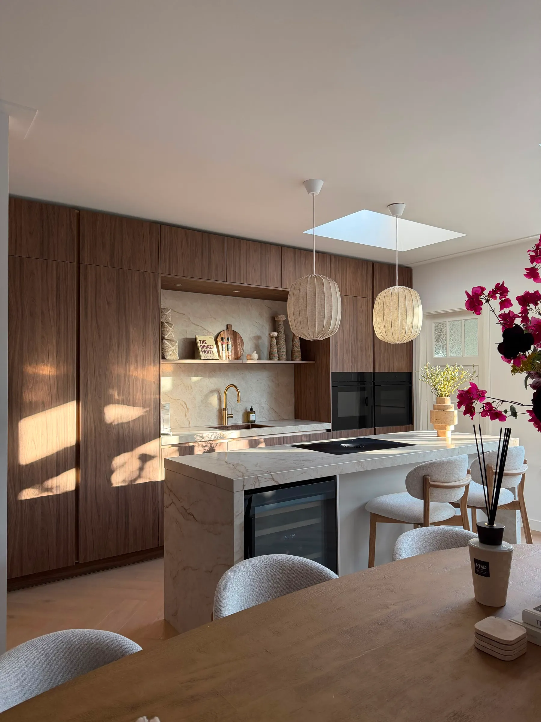 Notenhouten keuken met een marmeren kookeiland, twee linnen hanglampen en een dakraam